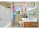 Bathroom showcasing a tub with a shower curtain, window and a single sink vanity at 907 Sikes Mill Rd, Monroe, NC 28110