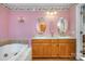Bathroom featuring a double vanity, oval mirrors, light sconces and a tiled soaking tub at 907 Sikes Mill Rd, Monroe, NC 28110