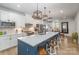 Modern kitchen featuring an oversized center island with barstool seating, pendant lighting, and white cabinetry at 980 Prince Garrett Way, Denver, NC 28037