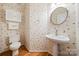 Charming powder room with patterned wallpaper, a pedestal sink, and a decorative round mirror at 10434 Blackstock Rd, Huntersville, NC 28078