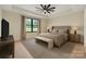 This bedroom features a neutral palette, a tray ceiling with fan, and a large window overlooking green space at 1141 Harper Lee Dr, Newton, NC 28658
