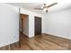 Bedroom with wood floors, ceiling fan and an open dark brown door leading to a hallway at 1348 Green Oaks Ln # L, Charlotte, NC 28205