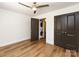 Bedroom with wood floors, ceiling fan and a stacked washer and dryer behind dark brown doors at 1348 Green Oaks Ln # L, Charlotte, NC 28205