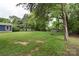 Large, well-maintained backyard featuring mature trees, green grass, and a fire pit area at 15333 Catawba S Cir, Matthews, NC 28104