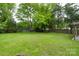 Expansive backyard with lush green grass, mature trees, and a charming fire pit area at 15333 Catawba S Cir, Matthews, NC 28104