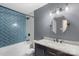 Bright bathroom with blue tiled shower, round mirror, and vanity with marble countertop at 15333 Catawba S Cir, Matthews, NC 28104