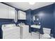 Modern laundry room with blue walls, white cabinets, washer, dryer, sink, and toilet at 15333 Catawba S Cir, Matthews, NC 28104
