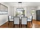 Bright dining room featuring a glass top table, white chairs, hardwood floors, and a modern light fixture at 1700 Emerywood Dr, Charlotte, NC 28210