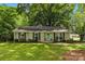 Charming brick ranch home with a manicured lawn, black shutters, and a vibrant teal front door at 1700 Emerywood Dr, Charlotte, NC 28210
