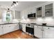 Bright renovated kitchen boasts stainless steel appliances, hardwood floors and white cabinets at 1700 Emerywood Dr, Charlotte, NC 28210