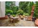 Enjoy an outdoor barbecue on the stone patio featuring a dining area, a grill, and a brick fireplace at 2000 Ferncliff Rd, Charlotte, NC 28211