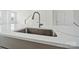 Close-up of a kitchen sink with a modern faucet, white countertop, and view of the staircase at 2134 Barrowcliffe Nw Dr # 0006, Concord, NC 28027