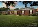 Charming brick home with black shutters, manicured lawn, and covered front porch at sunset at 301 Museum Rd, Statesville, NC 28625