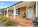 Welcoming covered front porch with brick flooring, white columns, and decorative plants at 301 Museum Rd, Statesville, NC 28625