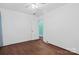 Simple bedroom with wood floors, a ceiling fan, white walls, and a doorway leading to another room at 4608 Beatties Ford Rd, Charlotte, NC 28216