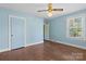 Pastel blue bedroom with hardwood floors, two windows, and a classic ceiling fan at 4608 Beatties Ford Rd, Charlotte, NC 28216