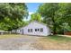 Charming exterior of white-sided home with a gated yard surrounded by lush trees at 4608 Beatties Ford Rd, Charlotte, NC 28216
