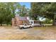 Exterior view showcasing a brick and siding home with a gravel driveway and lush green trees at 4608 Beatties Ford Rd, Charlotte, NC 28216