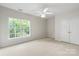 Serene bedroom featuring neutral carpet, a ceiling fan, and a window offering natural light and views of the surrounding trees at 601 Carver Pond Ln, Waxhaw, NC 28173