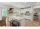 Bright kitchen boasts white cabinets, an island with seating, stainless steel appliances, and hardwood floors at 601 Carver Pond Ln, Waxhaw, NC 28173