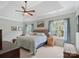 This comfortable main bedroom boasts a tray ceiling, a ceiling fan, and large windows for natural light at 7627 Woodcrest Dr, Stanley, NC 28164