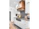 Bright kitchen with white cabinets, a wooden range hood, and a black backsplash, complemented by stylish lighting at 120 Lakeshore Dr, Mooresville, NC 28117