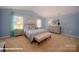 Light-filled bedroom with blue walls, a tufted headboard, two windows, and carpet flooring at 136 Mary Locke Way, Statesville, NC 28677