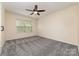 Cozy bedroom with ceiling fan and plush gray carpeting and natural light through a bright window at 15536 Oleander Dr # L228, Charlotte, NC 28278
