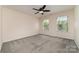 Spacious bedroom with plush gray carpeting, a ceiling fan, and ample natural light through bright windows at 15536 Oleander Dr # L228, Charlotte, NC 28278