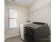 Functional laundry room with modern gray washer and dryer, plus storage shelves and window at 15536 Oleander Dr # L228, Charlotte, NC 28278