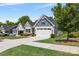 A charming home showcasing a two-car garage, manicured lawn, and stylish architectural details under a bright blue sky at 1747 Slippery Rock Ln, Monroe, NC 28112