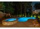 Beautiful swimming pool and jacuzzi surrounded by lush landscaping at night at 19507 Dufour Ct, Cornelius, NC 28031
