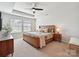 Comfortable main bedroom featuring tray ceiling, large bed, side tables and a large window at 2678 Wedgewood Ct, Denver, NC 28037