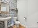 Stylish powder room featuring patterned wallpaper, a pedestal sink, and modern fixtures at 2678 Wedgewood Ct, Denver, NC 28037