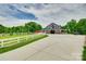 Spacious barn with covered porch and a driveway surrounded by green grass, white fencing and mature trees at 3091 Old Meeting House Rd, Sharon, SC 29742