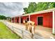 Red horse barn with white trim and horses standing outside the stalls at 3091 Old Meeting House Rd, Sharon, SC 29742