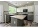Well-lit kitchen with island, gray cabinets, black appliances, and a view from the window at 3224 Dunbar Ln, Fort Mill, SC 29707