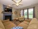 Bright living room with fireplace, ceiling fan, and large windows offering views of the landscaped yard at 3224 Dunbar Ln, Fort Mill, SC 29707