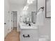 Bright bathroom with a double vanity, black fixtures, and wood-look flooring, next to a walk-in closet at 3314 & 3316 Cedarhurst Dr, Charlotte, NC 28269