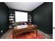 Office featuring dark accent walls, an area rug, and built in bookshelves at 4245 Millstream Rd, Denver, NC 28037