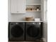Modern laundry room with front-loading washer/dryer, white cabinets, and open shelving for organized storage at 443 Brandon St, Davidson, NC 28036
