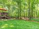 Spacious backyard with a deck with an umbrella table set, surrounded by lush trees, perfect for outdoor enjoyment at 5417 Bedfordshire Ave, Harrisburg, NC 28075