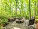 Backyard fire pit with stone seating and lush green surrounding landscape and mature trees at 5417 Bedfordshire Ave, Harrisburg, NC 28075