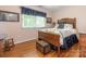 Cozy bedroom featuring hardwood floors, a wooden bed frame, and natural light at 5417 Bedfordshire Ave, Harrisburg, NC 28075