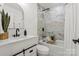 Bright bathroom features marble shower and tub, sleek vanity with black fixtures, and large arched mirror at 5910 Grosner Pl, Charlotte, NC 28211