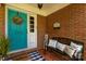 Inviting front porch featuring a turquoise door, decorative wreath, and cozy bench with throw pillows at 709 Plantation Rd, Lancaster, SC 29720