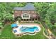 Aerial view showcases a brick house with backyard lagoon-style pool, in-ground spa, patio, and landscaped yard at 7812 Seton House Ln, Charlotte, NC 28277