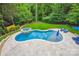 Aerial view showcasing the backyard's lagoon-shaped pool, in-ground hot tub, patio, and surrounding lush landscaping at 7812 Seton House Ln, Charlotte, NC 28277