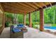 Covered patio space with brick pillars, outdoor seating, and a view of the landscaped backyard and pool at 7812 Seton House Ln, Charlotte, NC 28277