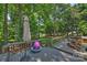 Outdoor deck with an umbrella, pink trampoline and wooden chairs looking out to a green, wooded yard at 7833 Taymouth Ln, Charlotte, NC 28269